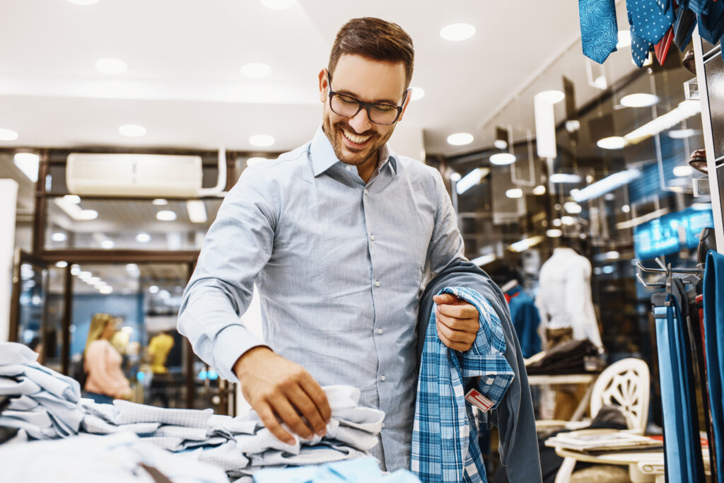 Portrait of handsome young man buying clothes in the store.