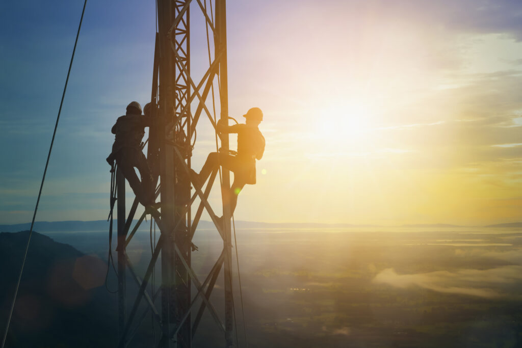 Silhouette electrician work on high ground heavy industry concept. Construction of the extension of high voltage in high voltage stations safely and systematically over blurred natural background